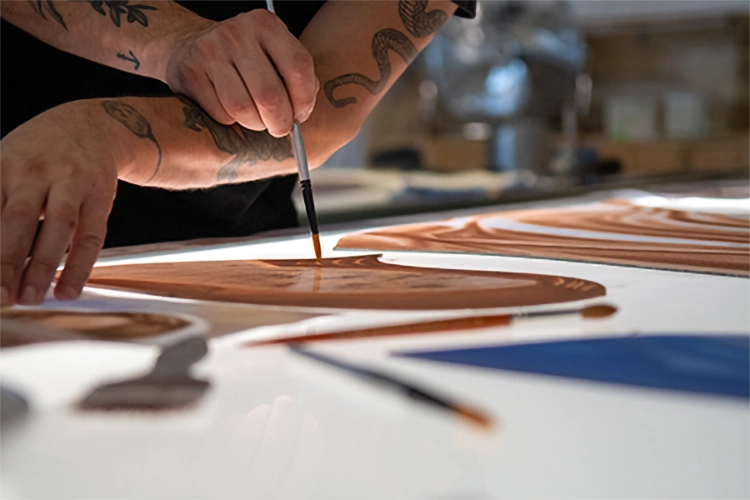 Detail of a glass artist painting a mouth-blown glass with the grisaille technique